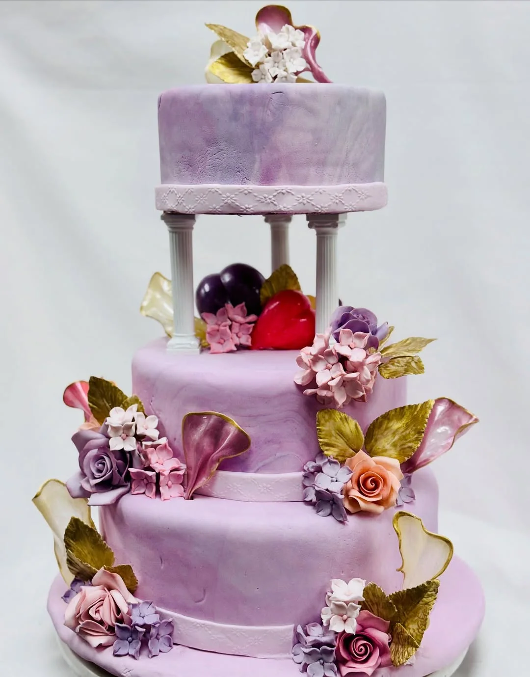 Lilas — three-tier bridal cake with hand-painted lavender fondant, sugar roses and gilded gum-paste foliage